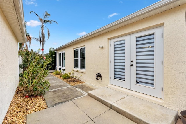 entrance to property with a patio, french doors, and stucco siding