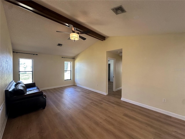 living area with vaulted ceiling with beams, wood finished floors, visible vents, and baseboards