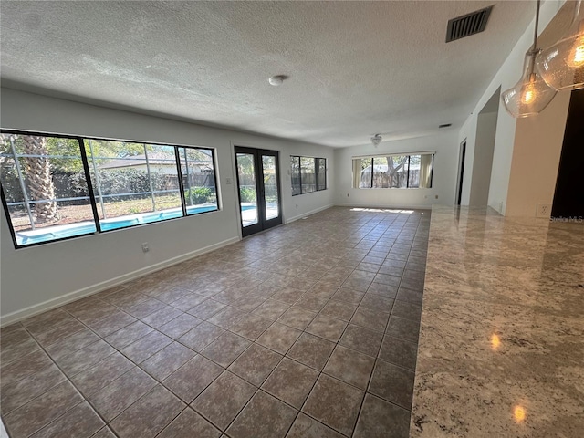 spare room with a textured ceiling, french doors, visible vents, and baseboards