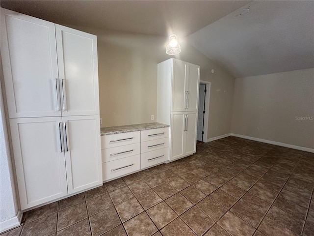 additional living space with vaulted ceiling, dark tile patterned floors, and baseboards