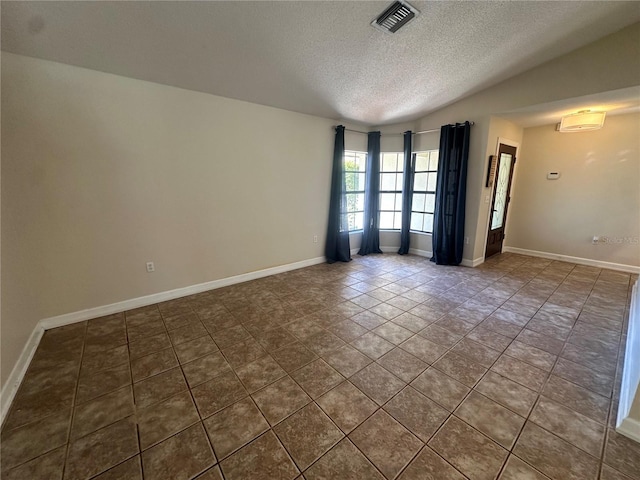 spare room featuring lofted ceiling, visible vents, a textured ceiling, and baseboards