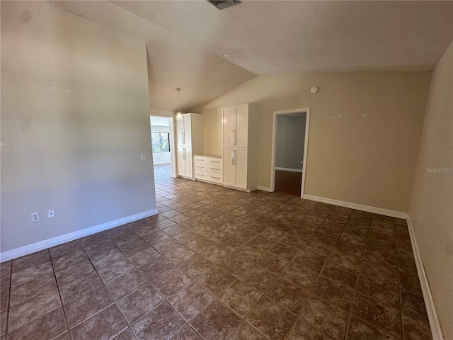 spare room featuring lofted ceiling and baseboards