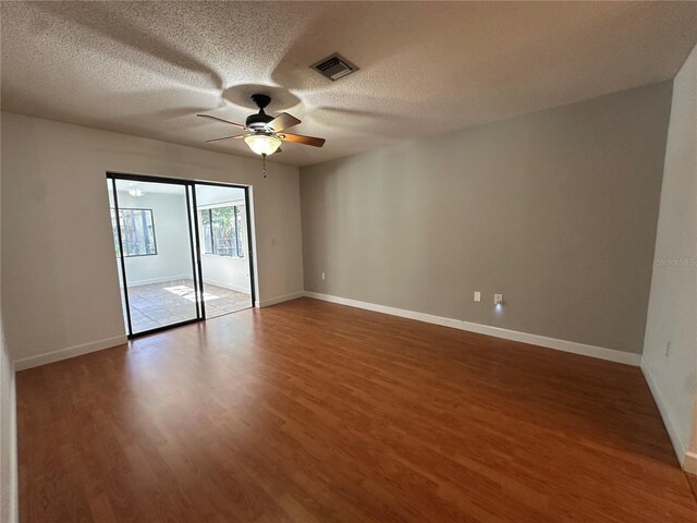 spare room featuring a ceiling fan, visible vents, baseboards, and wood finished floors