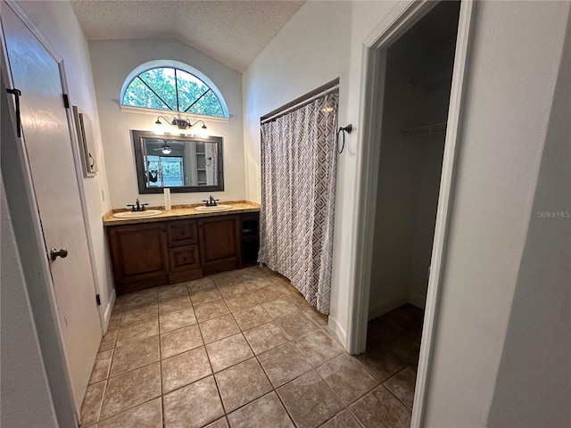 bathroom featuring lofted ceiling, tile patterned flooring, a textured ceiling, and a sink