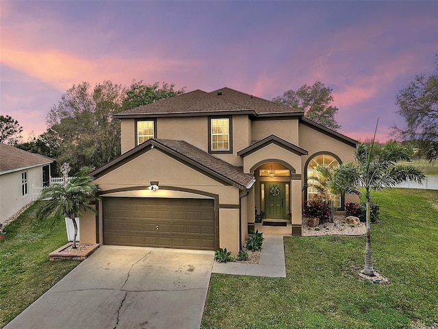 view of front of home with a garage, concrete driveway, a front yard, and stucco siding