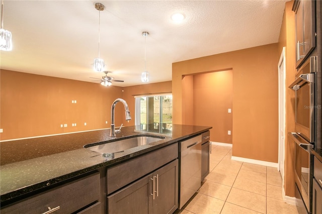 kitchen featuring dark stone countertops, light tile patterned floors, stainless steel appliances, a sink, and pendant lighting