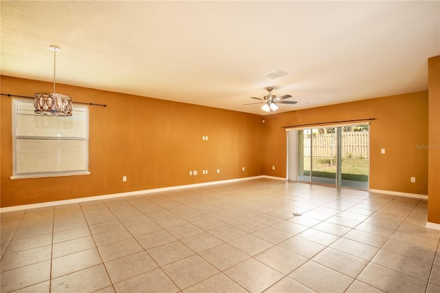 unfurnished room with light tile patterned floors, visible vents, ceiling fan with notable chandelier, and baseboards