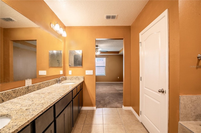 full bath featuring tile patterned flooring, visible vents, double vanity, a textured ceiling, and a sink