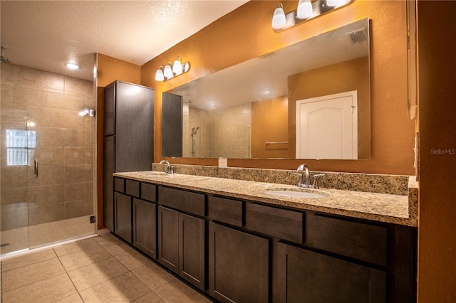 bathroom featuring visible vents, a sink, a shower stall, tile patterned flooring, and double vanity