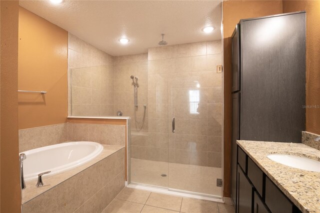 bathroom with vanity, tile patterned flooring, a shower stall, a textured ceiling, and a garden tub