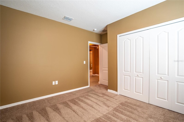 unfurnished bedroom featuring visible vents, baseboards, carpet flooring, a closet, and a textured ceiling