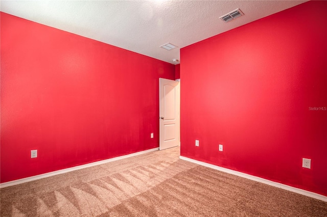 spare room with visible vents, a textured ceiling, baseboards, and carpet