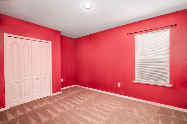 unfurnished bedroom with a closet, a textured ceiling, baseboards, and carpet floors