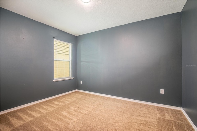 carpeted spare room with baseboards and a textured ceiling