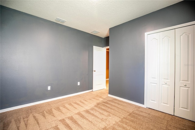 unfurnished bedroom featuring visible vents, baseboards, carpet flooring, a closet, and a textured ceiling