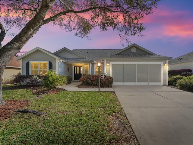 ranch-style house featuring a garage, roof with shingles, concrete driveway, and a front yard