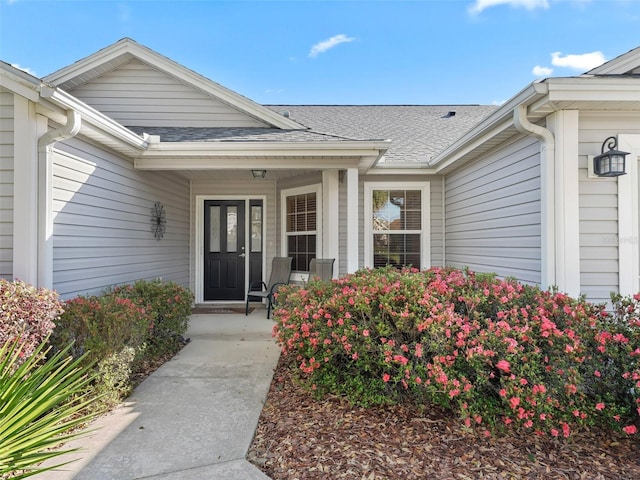 property entrance with a porch and roof with shingles