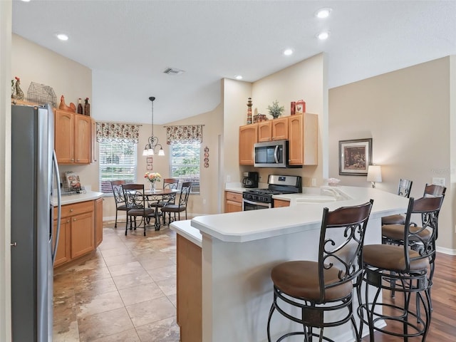 kitchen featuring a breakfast bar, visible vents, appliances with stainless steel finishes, a sink, and a peninsula