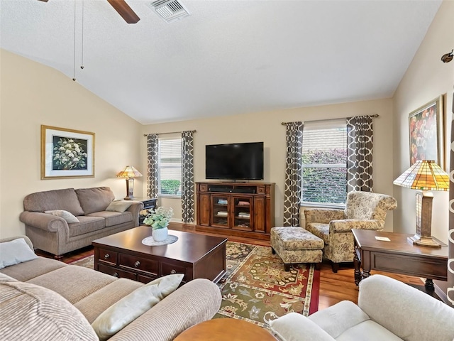 living room with ceiling fan, visible vents, vaulted ceiling, and wood finished floors