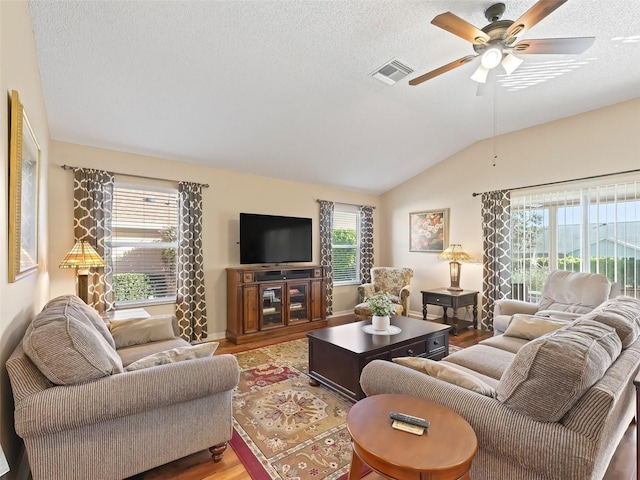 living area with visible vents, lofted ceiling, ceiling fan, wood finished floors, and a textured ceiling