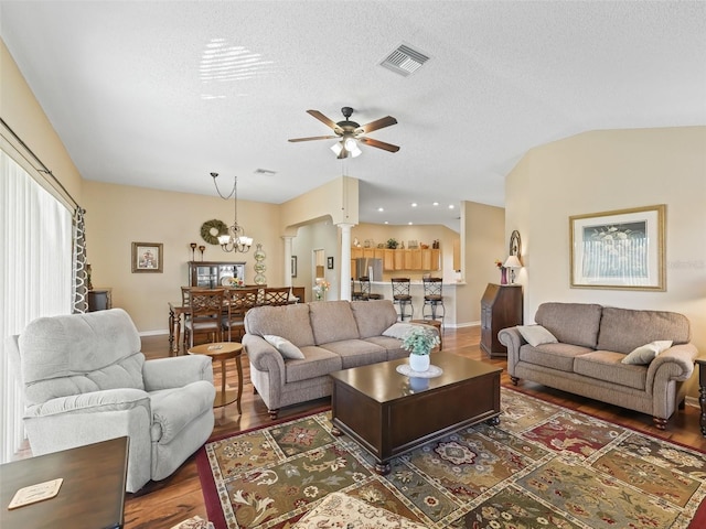 living room with a textured ceiling, wood finished floors, visible vents, vaulted ceiling, and ornate columns