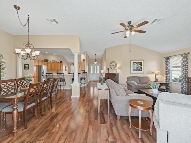 living room with vaulted ceiling, wood finished floors, visible vents, and ornate columns