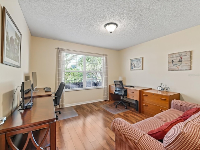 home office with a textured ceiling, baseboards, and wood finished floors