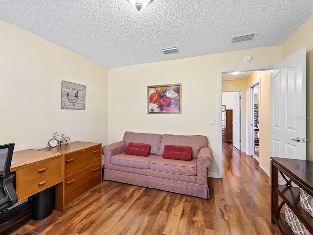 living room featuring a textured ceiling, wood finished floors, and visible vents