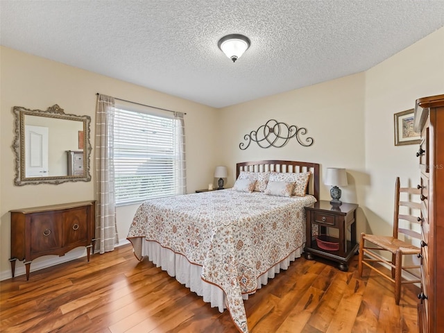 bedroom with a textured ceiling and wood finished floors