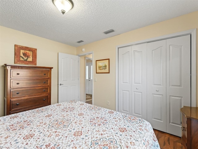 bedroom featuring a closet, visible vents, a textured ceiling, and dark wood-style flooring