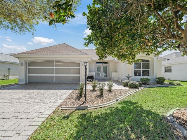 view of front facade with french doors, decorative driveway, stucco siding, a garage, and a front lawn