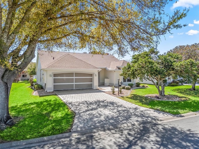 view of front facade featuring an attached garage, roof with shingles, decorative driveway, stucco siding, and a front yard