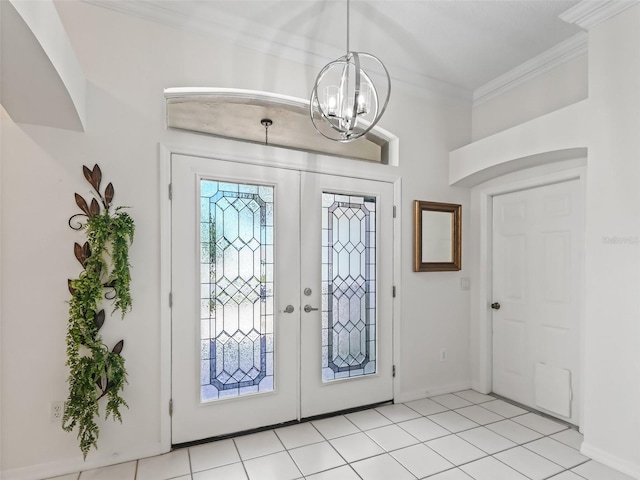 foyer entrance with a chandelier, french doors, ornamental molding, and light tile patterned floors