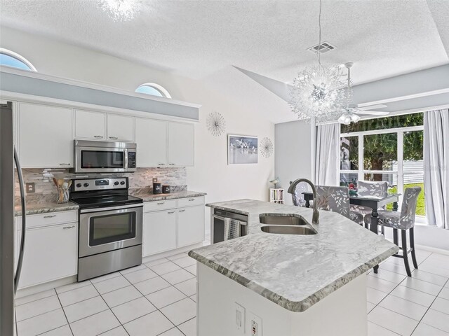 kitchen featuring visible vents, decorative backsplash, appliances with stainless steel finishes, a kitchen island with sink, and a sink