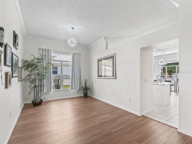 empty room featuring a sink, a wealth of natural light, wood finished floors, and an inviting chandelier