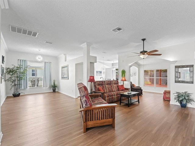 living area featuring ceiling fan with notable chandelier, wood finished floors, and visible vents