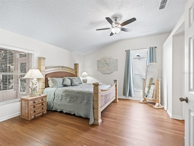 bedroom featuring a ceiling fan, visible vents, vaulted ceiling, and wood finished floors