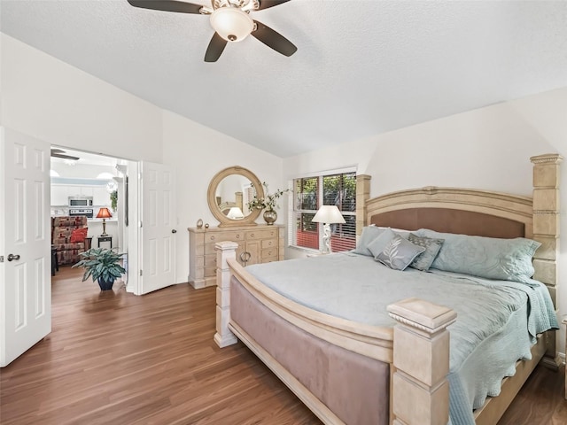 bedroom featuring lofted ceiling, ceiling fan, a textured ceiling, and wood finished floors