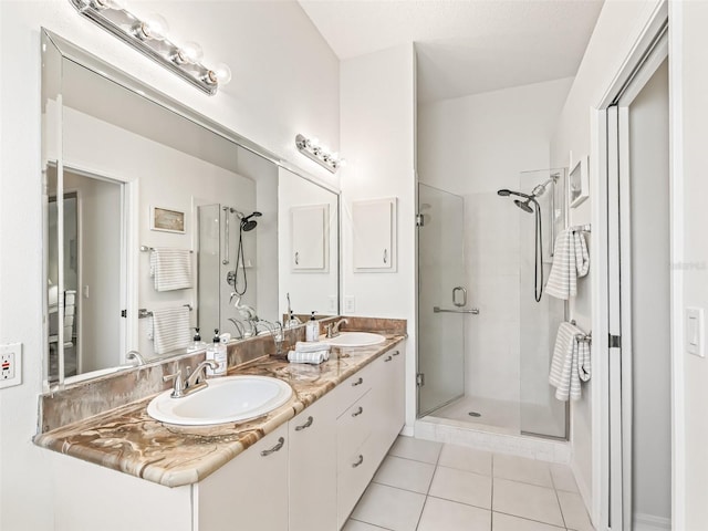 bathroom with a stall shower, tile patterned flooring, a sink, and double vanity