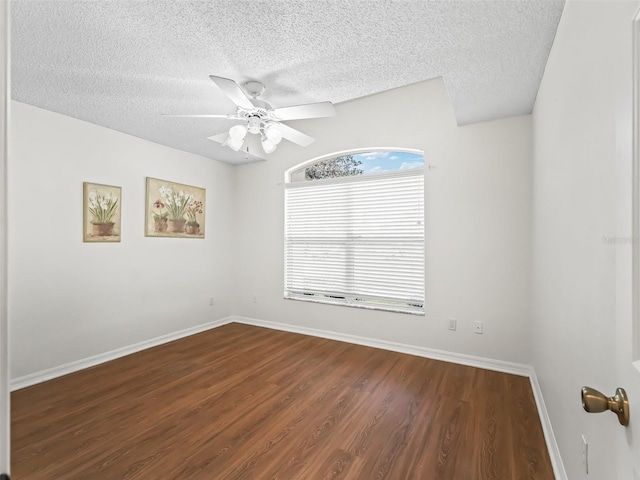 empty room with ceiling fan, a textured ceiling, baseboards, and wood finished floors