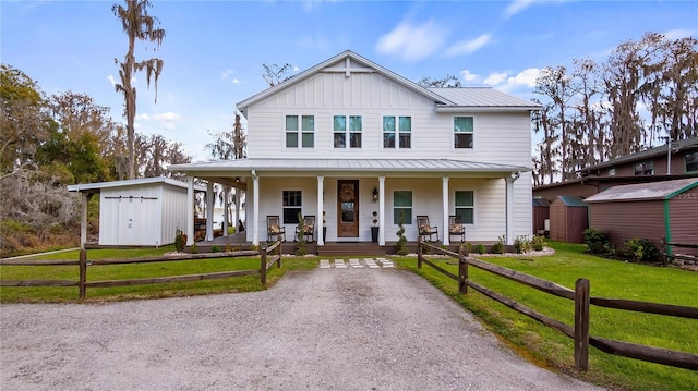 view of front of house featuring covered porch, fence, a shed, board and batten siding, and a front yard