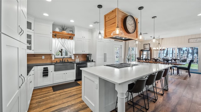 kitchen with a center island, visible vents, dark wood-type flooring, a sink, and dishwasher