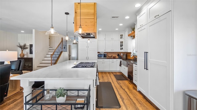 kitchen with appliances with stainless steel finishes, a center island, white cabinetry, and light wood-style flooring