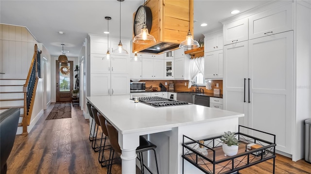 kitchen featuring stainless steel appliances, dark wood-type flooring, a breakfast bar, and white cabinets