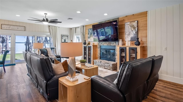 living area featuring recessed lighting, visible vents, ceiling fan, a stone fireplace, and wood finished floors