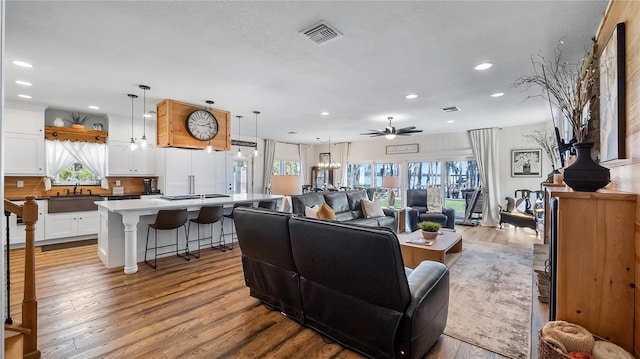 living area featuring a healthy amount of sunlight, light wood-style floors, ceiling fan, and visible vents