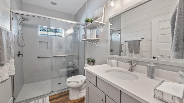 full bath featuring a stall shower, vanity, toilet, and wood finished floors