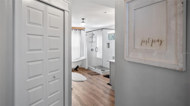 bathroom with a stall shower, a closet, and wood finished floors