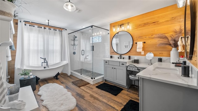 bathroom featuring wood finished floors, a soaking tub, a shower stall, and vanity