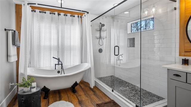 full bathroom featuring a stall shower, a freestanding bath, and wood finished floors